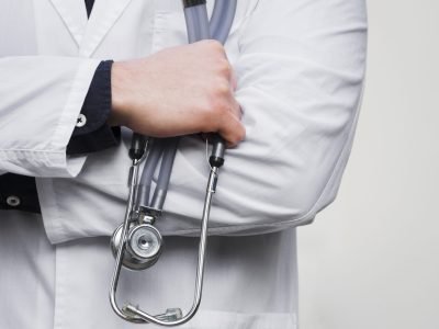 male-doctor-s-hand-holding-stethoscope-hand-against-white-backdrop